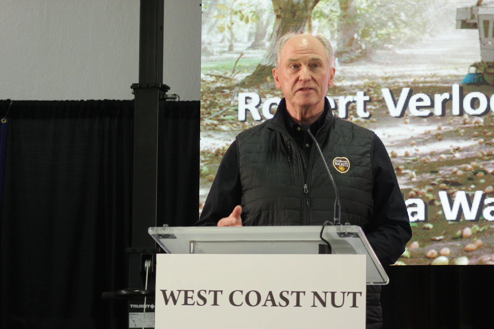 A presenter speaking at the West Coast Nut podium at North Valley Nut Conference in 2026.